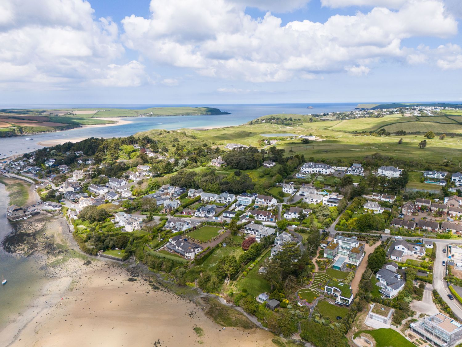 An aerial view of a coastal village with houses fields trees and a sandy beach at Landers Field in Rock