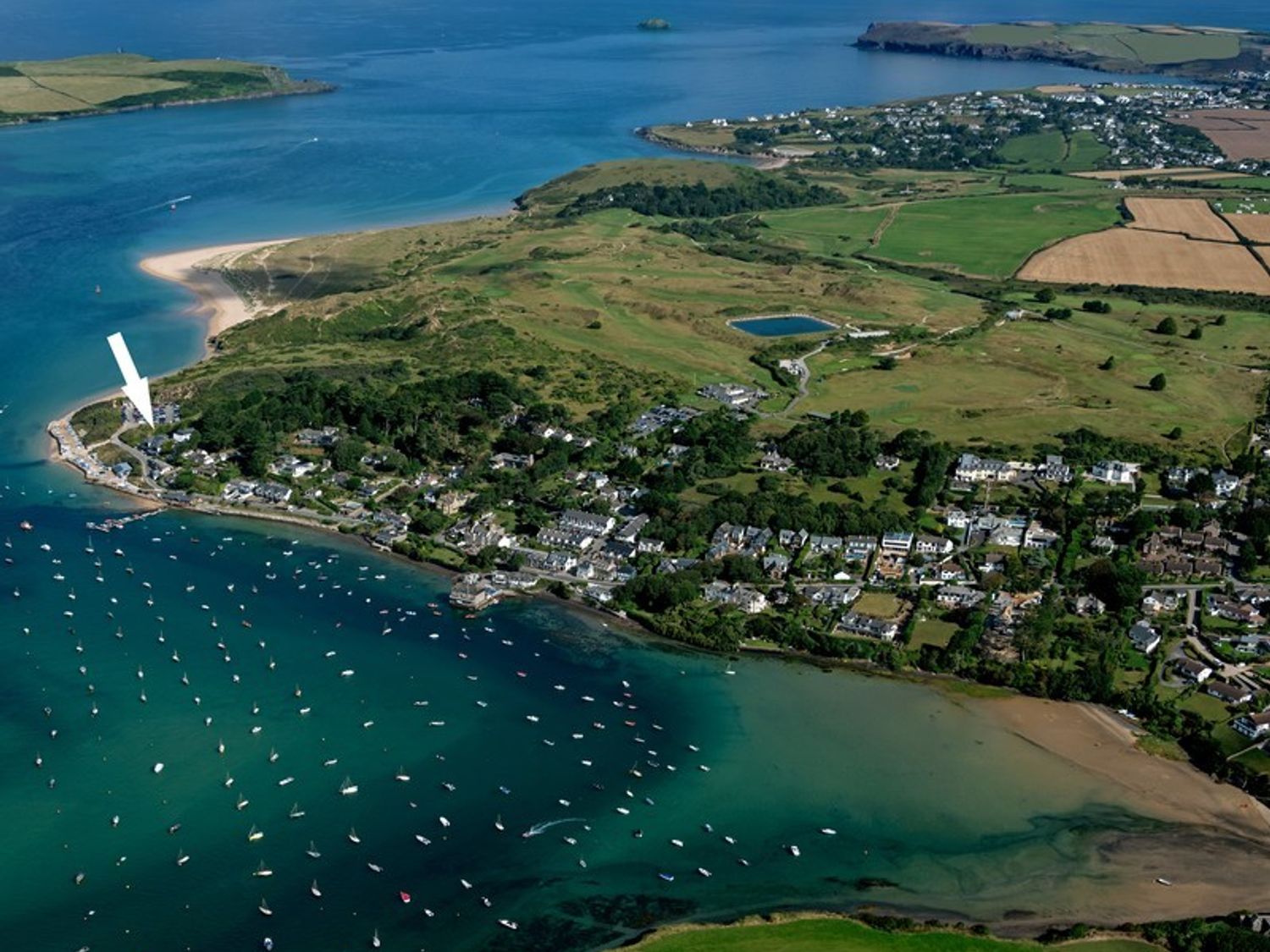 An aerial view of a coastal village with boats in the water and green fields in the background at Upper Deck in Rock