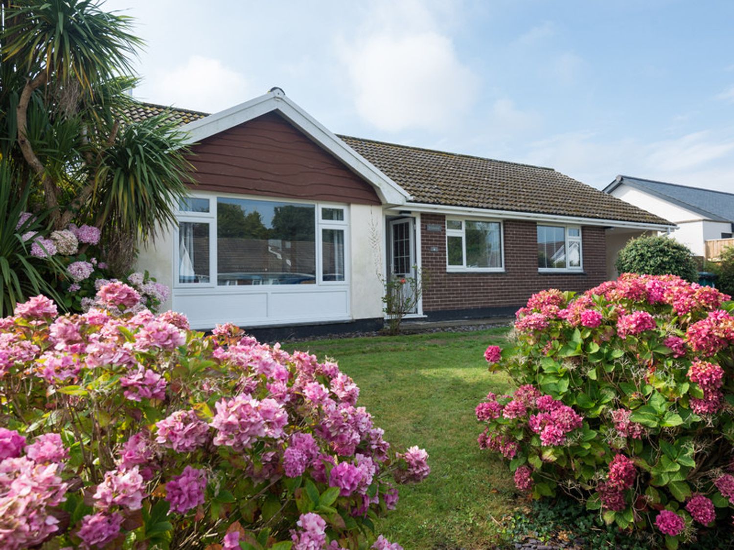 A bungalow with a lawn and pink flowering bushes at Greenaway 4 Rockhaven Gardens in Rock