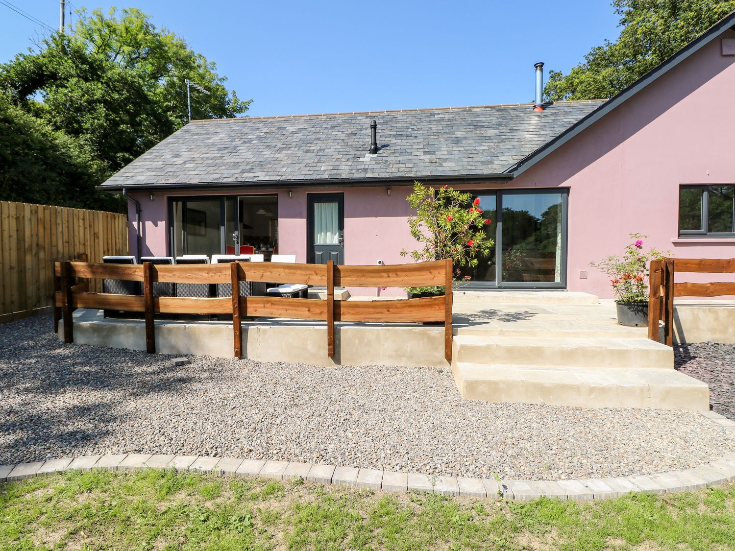 The exterior of a house with a gravel yard a wooden fence and stone steps leading to patio at 1 The Warren in Robeston Wathen near Narberth