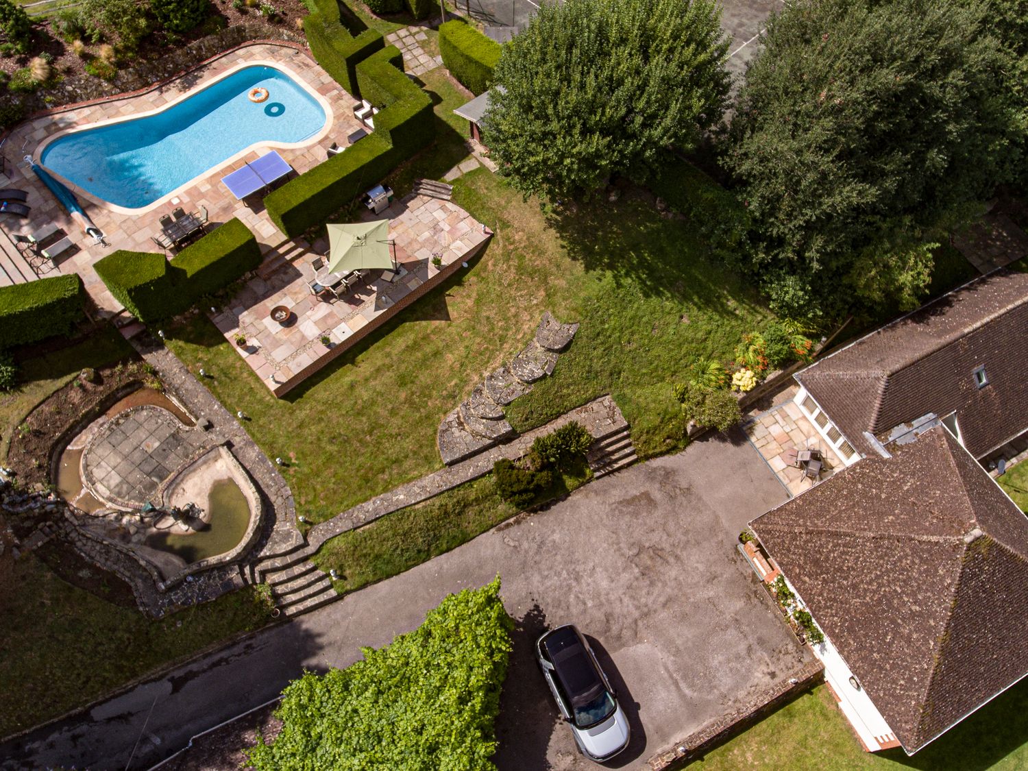 An aerial view of a property with a swimming pool patio garden driveway a parked car and a building at Heath Retreat in Buxted