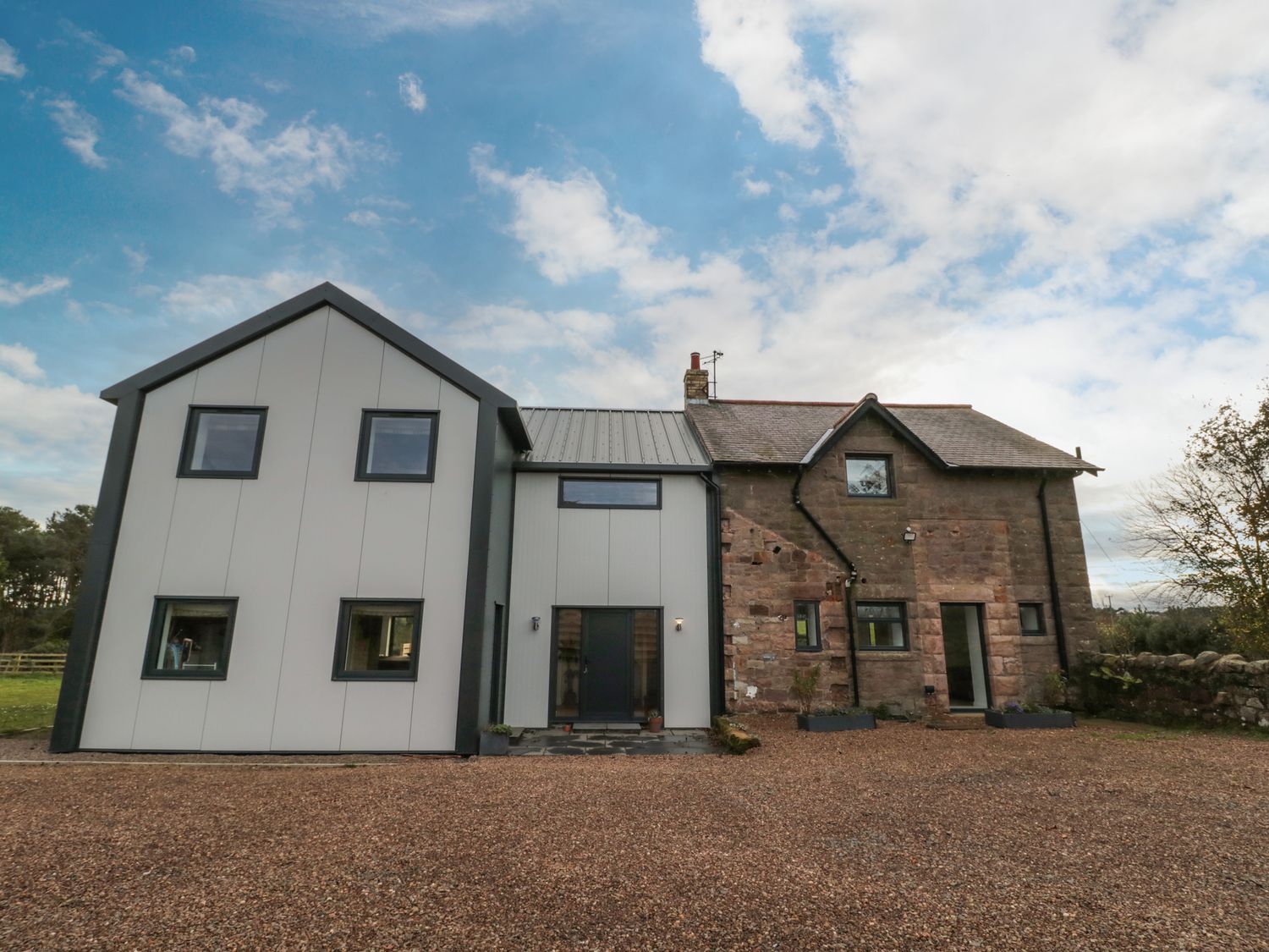 A house with a modern extension and stone facade with gravel driveway at Shepherds House in Lowick
