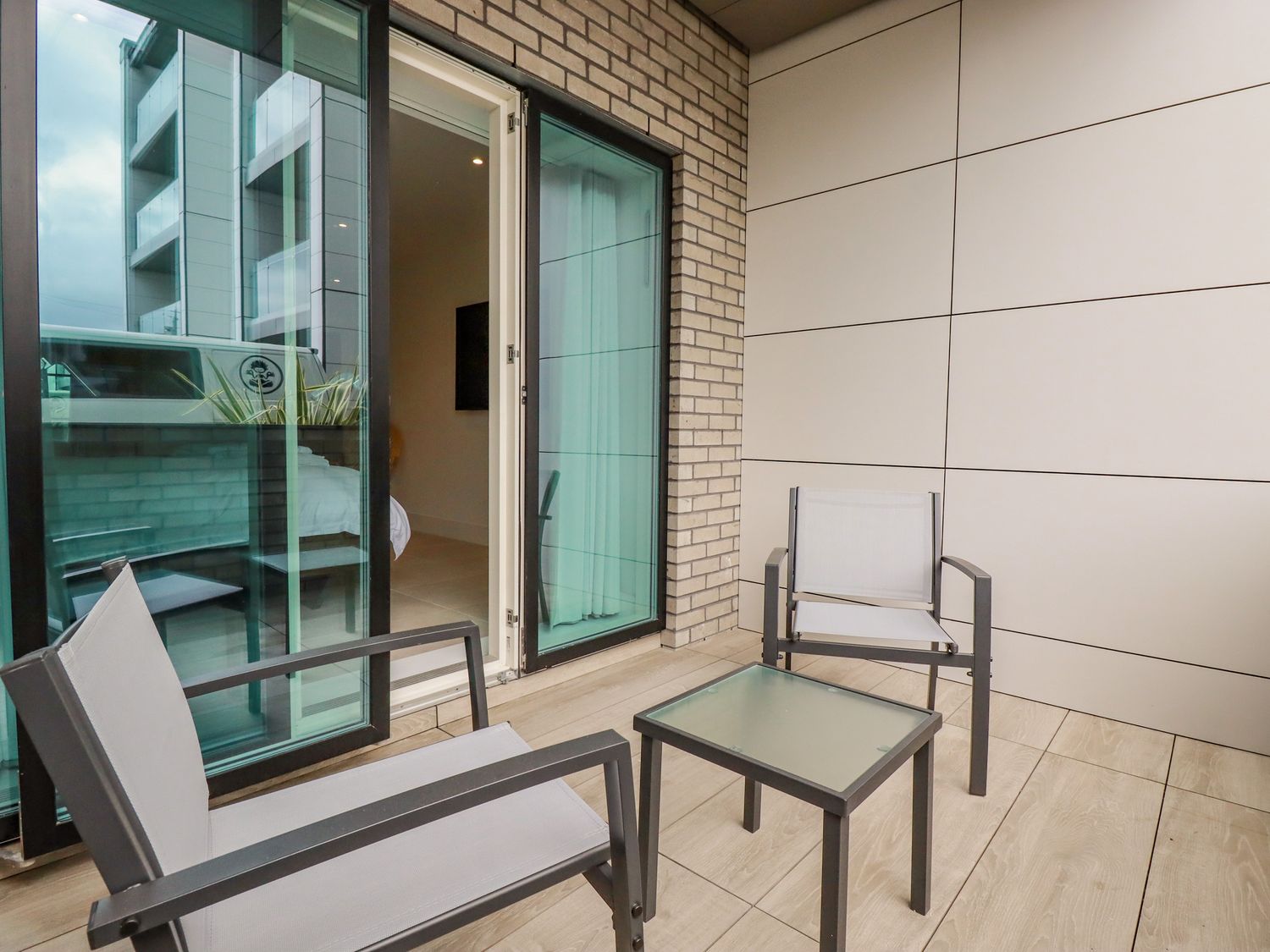 A balcony with two chairs and a small glass table next to a sliding glass door at 13 Cliff Edge in Newquay