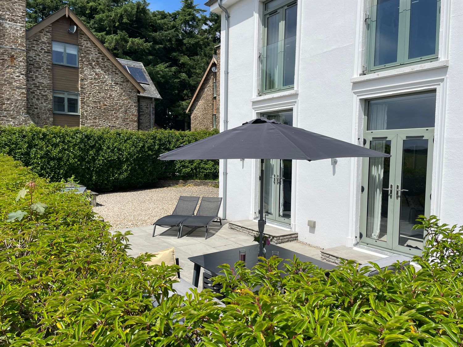 An outdoor area with deck chairs and a parasol at 2 The Manor House, Hillfield Village in Dartmouth