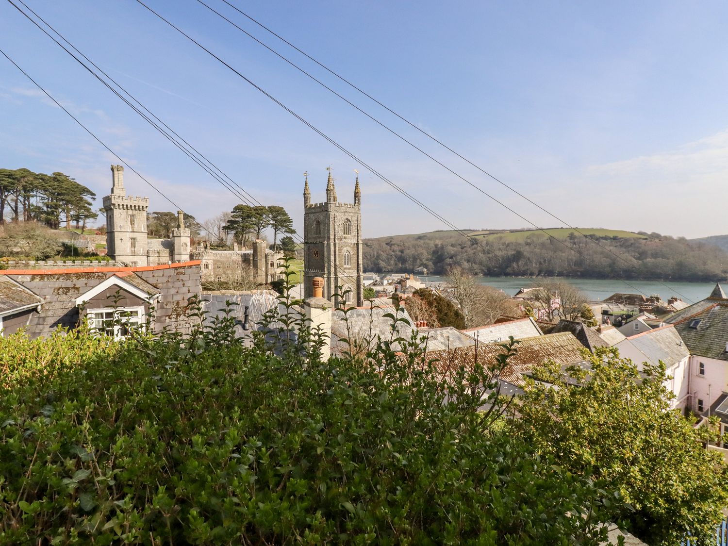 View over rooftops with church towers and water in the background at Driftwood in Fowey