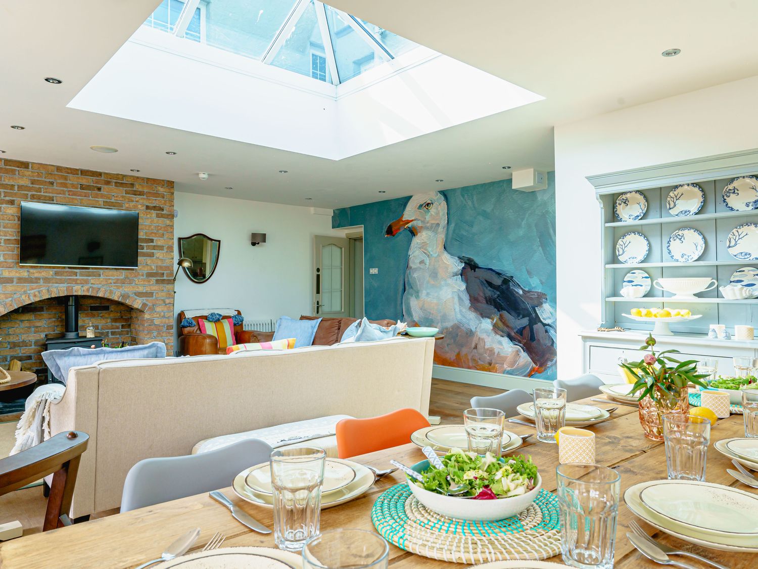 A living room with a dining area and a large bird mural at Y Graiglwyd Bull Bay near Amlwch