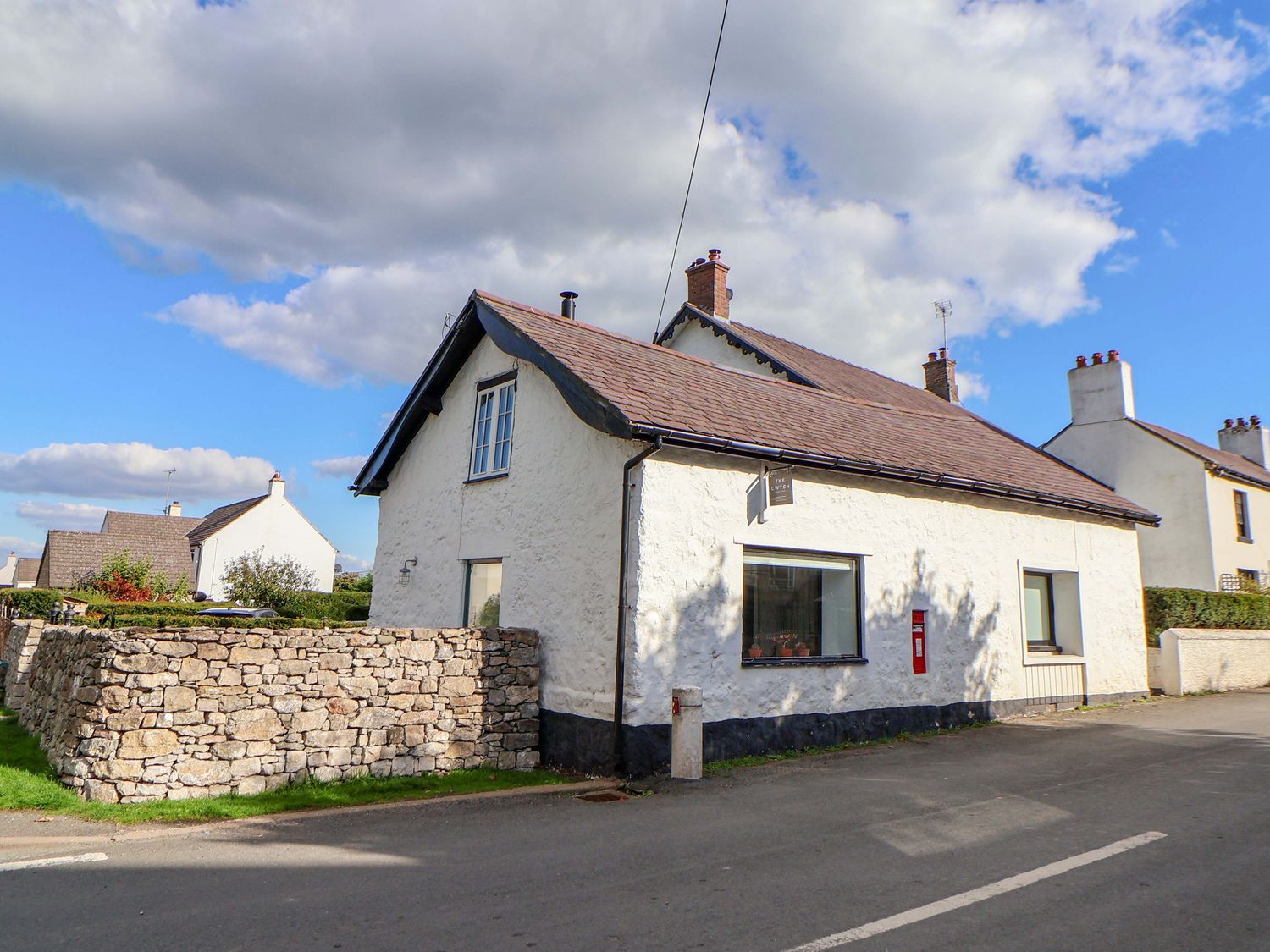 A house with a stone wall on the side at Cwtch in Mold