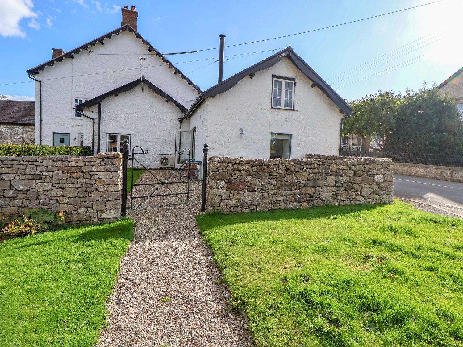 A house with a stone wall and gate in front at Cwtch in Mold