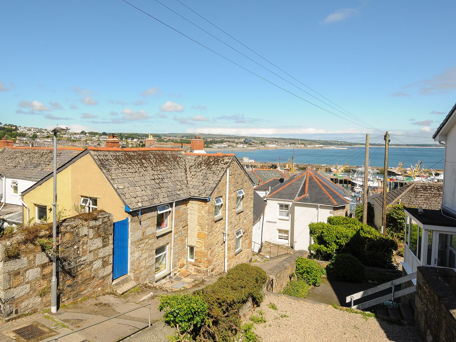 A coastal village with stone houses and a view of fishing boats in the harbor at Walter in Newlyn