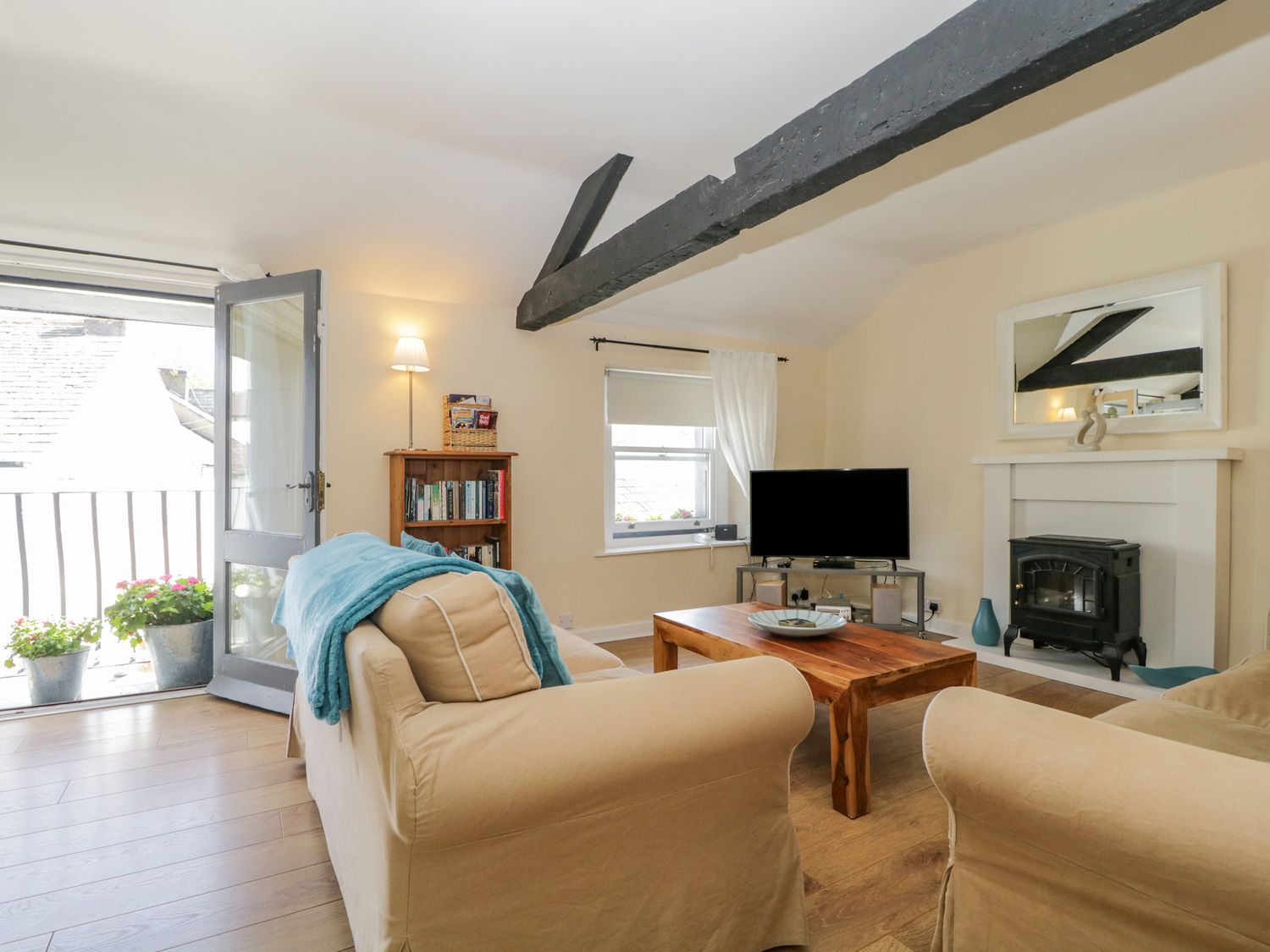 A living room with beige sofas wooden coffee table tv and bookshelf at The Old Mill in Keswick