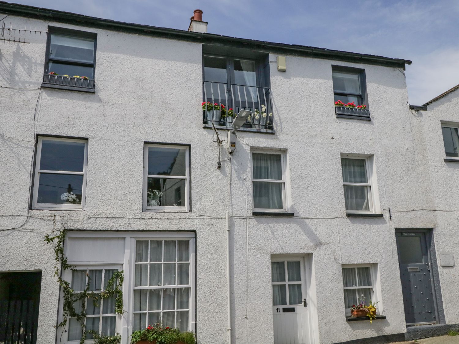A white multi-story building with several windows and flower pots outside at The Old Mill in Keswick
