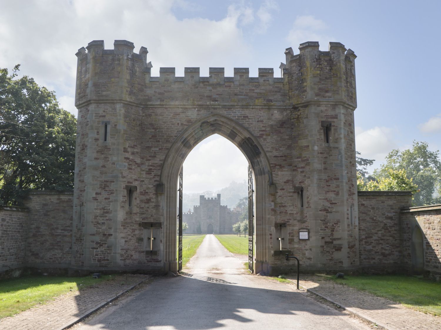 A stone archway entrance with battlements and two towers leading to a castle in the distance at Lower Venn Granary Apartment 1 Sutton St Nicholas near Bodenham