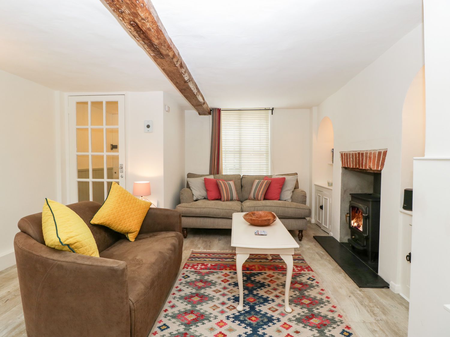 A living room with two sofas a coffee table a wood burning stove and a patterned rug at 7 Church Lane in Lymington