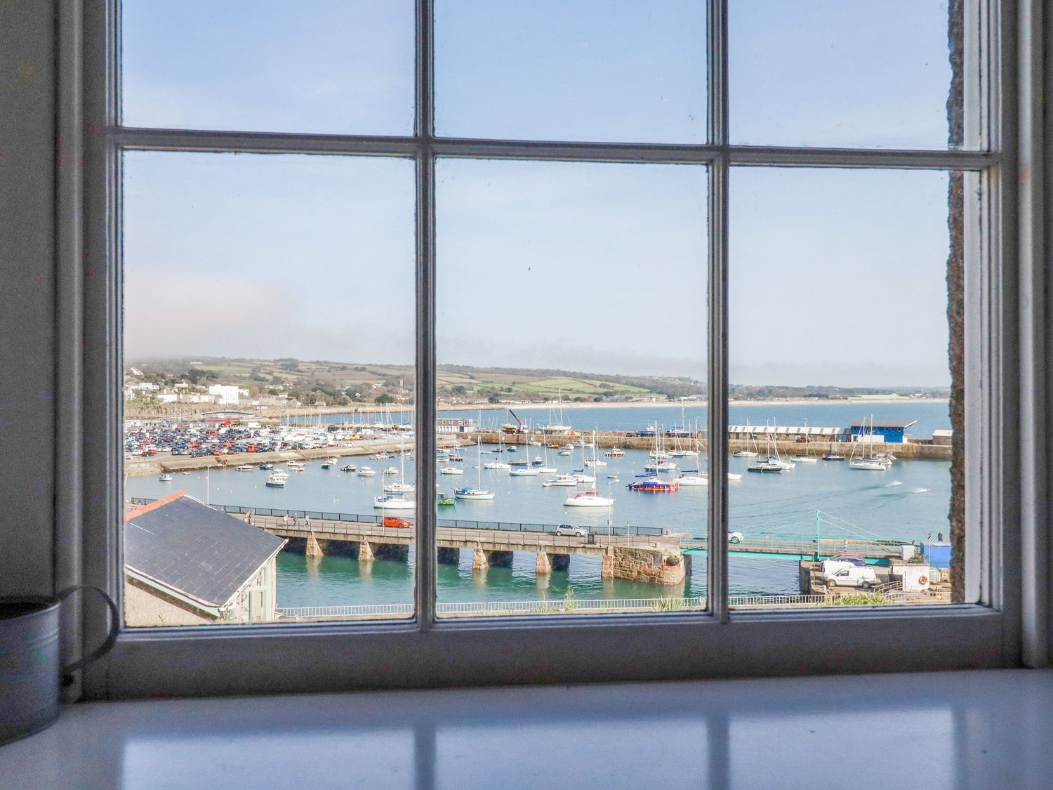 A view of a harbor with boats and a bridge seen through a window at 2 Bell Tower in Penzance