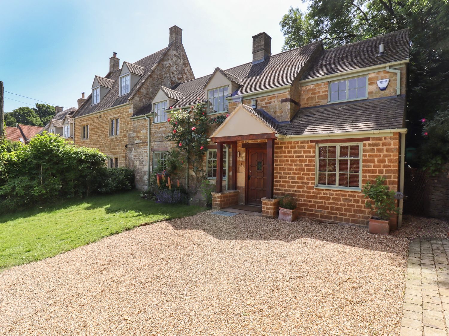 A traditional stone house with a gravel driveway and green lawn at 1 The Lane in Chipping Norton