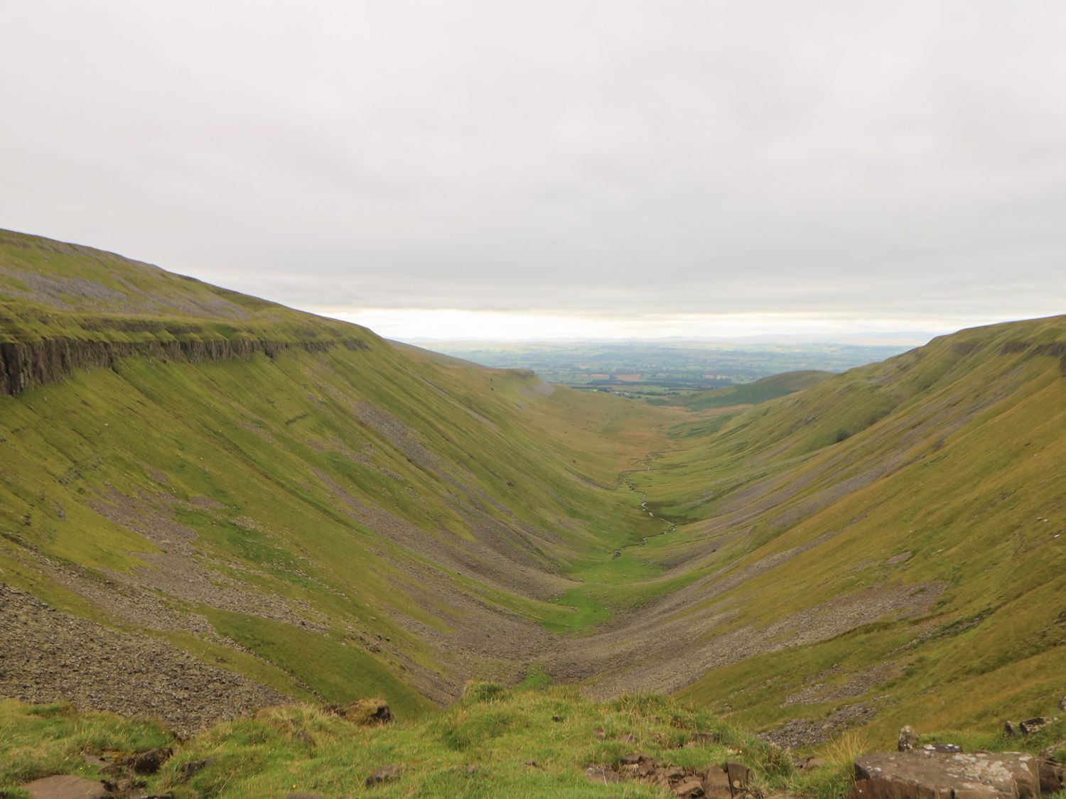 A valley with grassy slopes and a winding stream at 1 Yew Tree Cottages in Langwathby