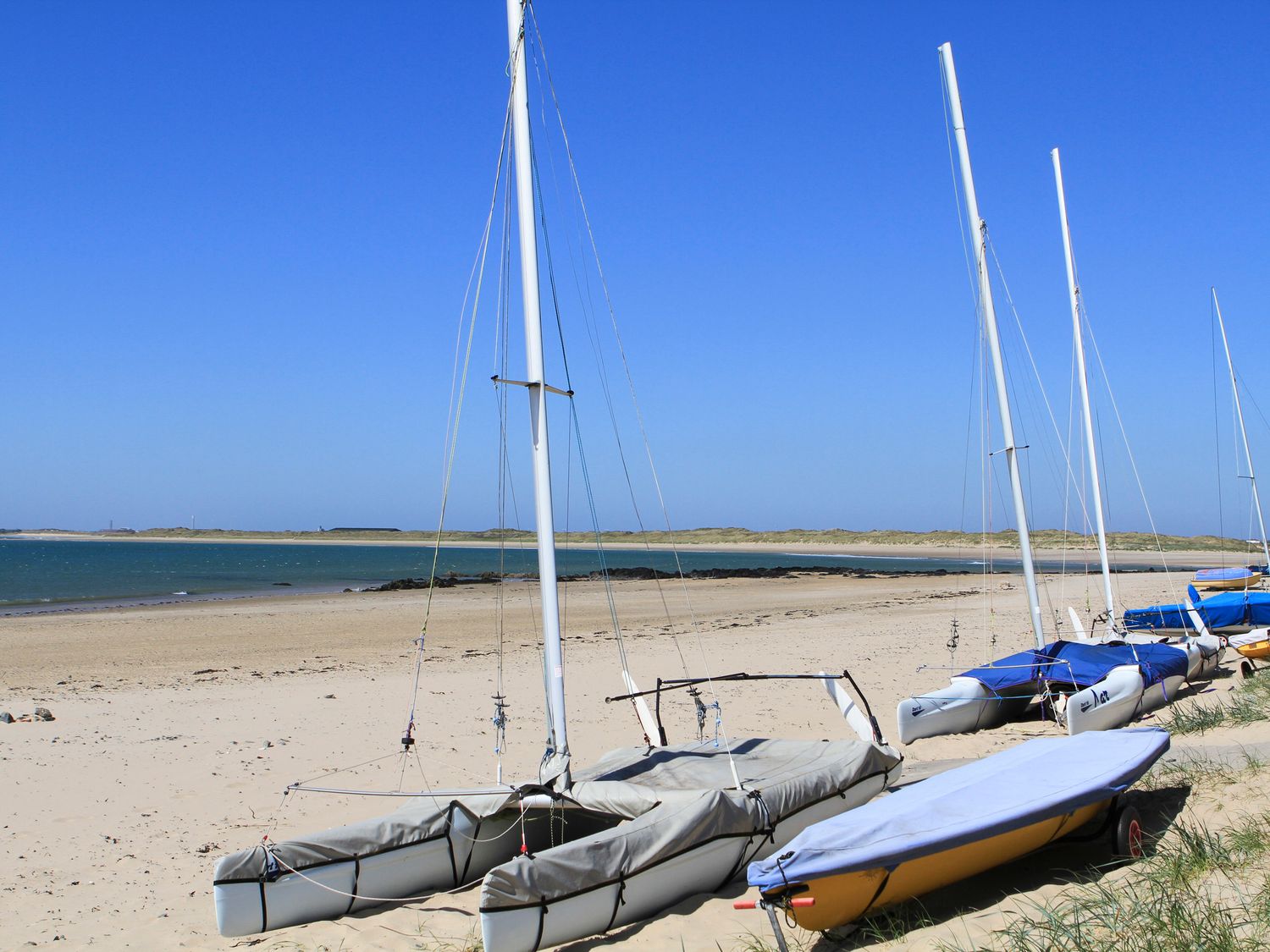Sailboats lined up on a sandy beach near the water at Trewan House Bryngwran near Rhosneigr Rhosneigr