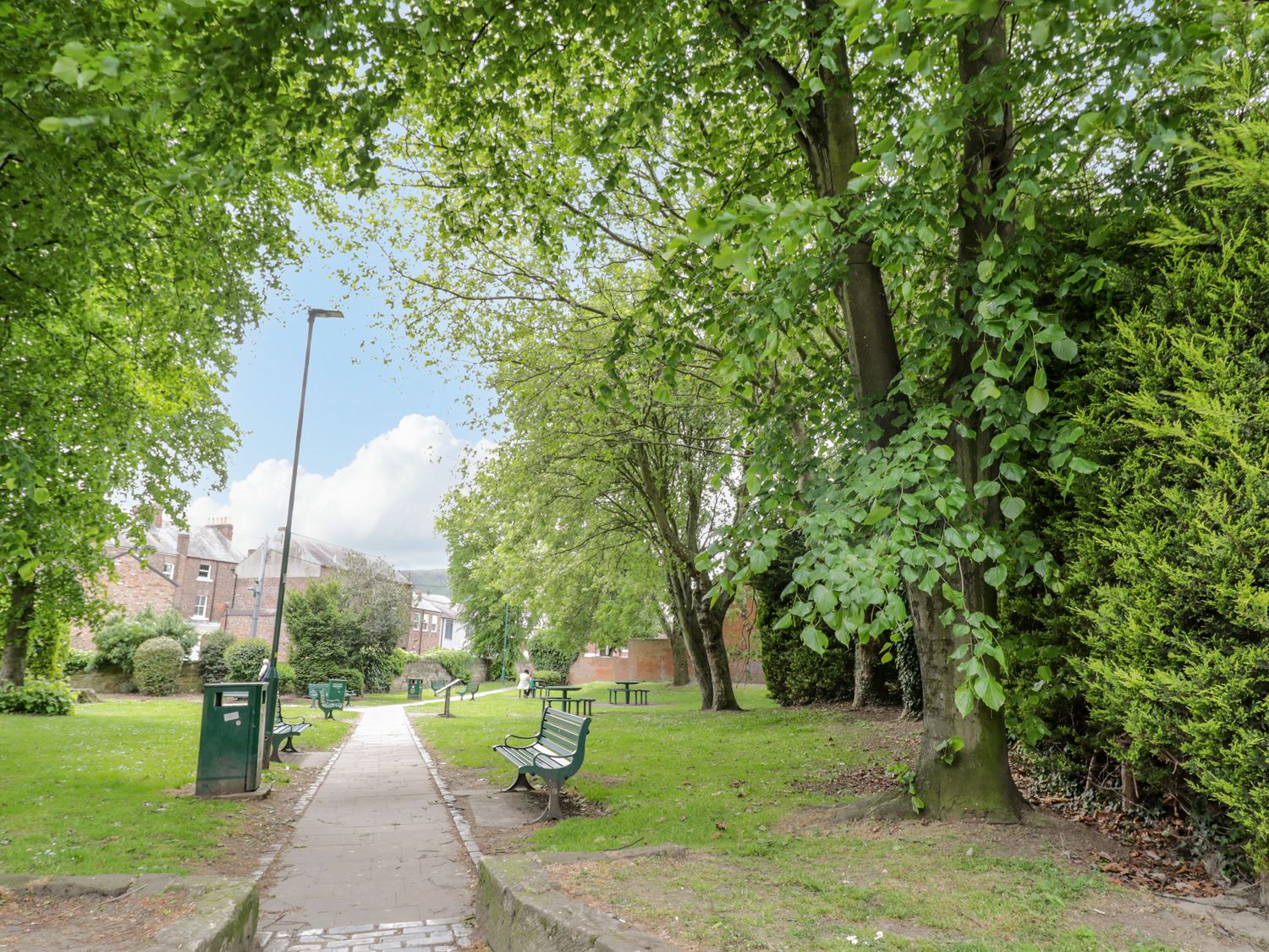 A park with benches trees and a pathway at Guisborough Town Hall in Guisborough