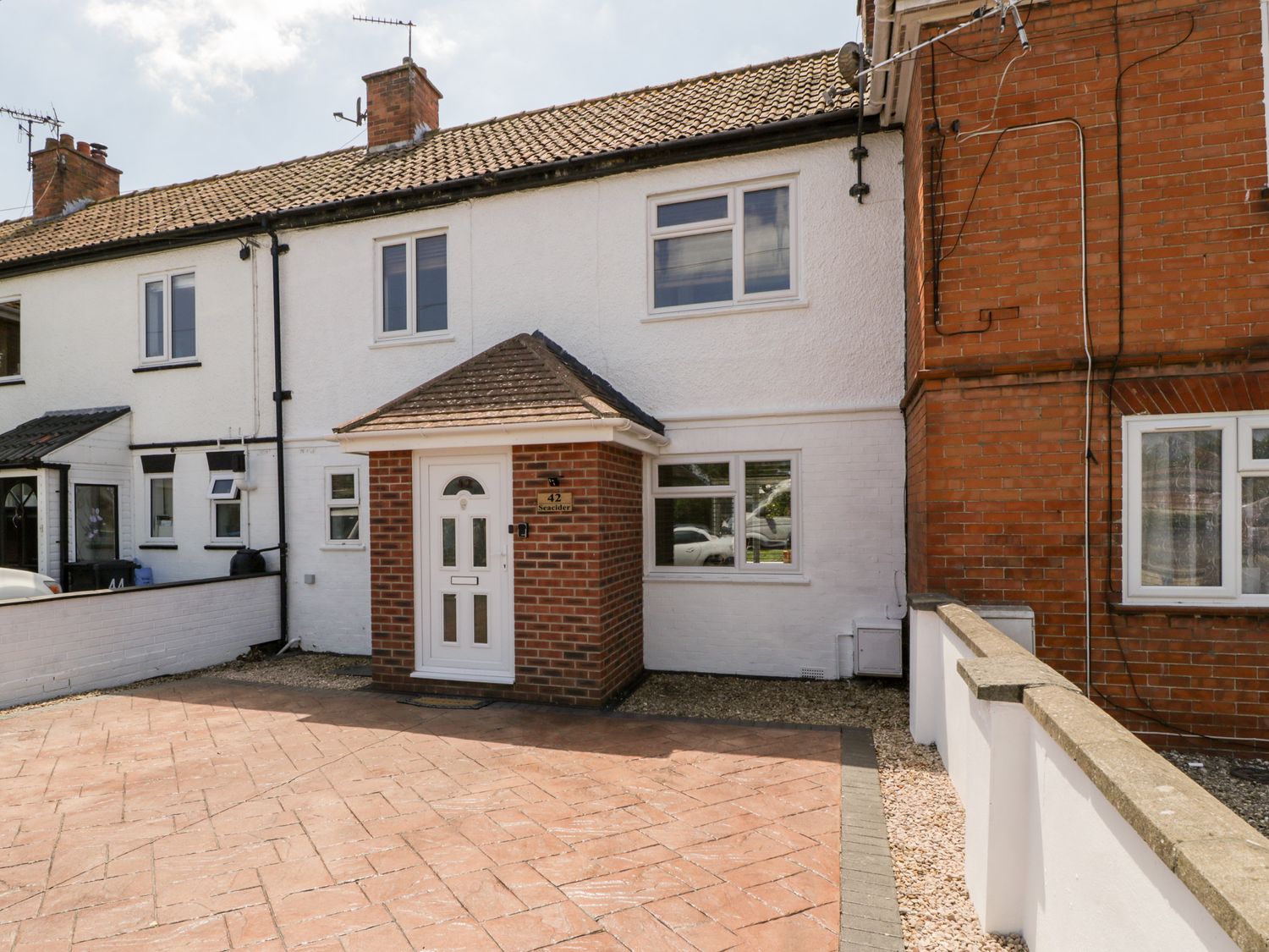 A front exterior view of a two-story terraced house with white walls and a small porch at Seacider in Burnham-On-Sea
