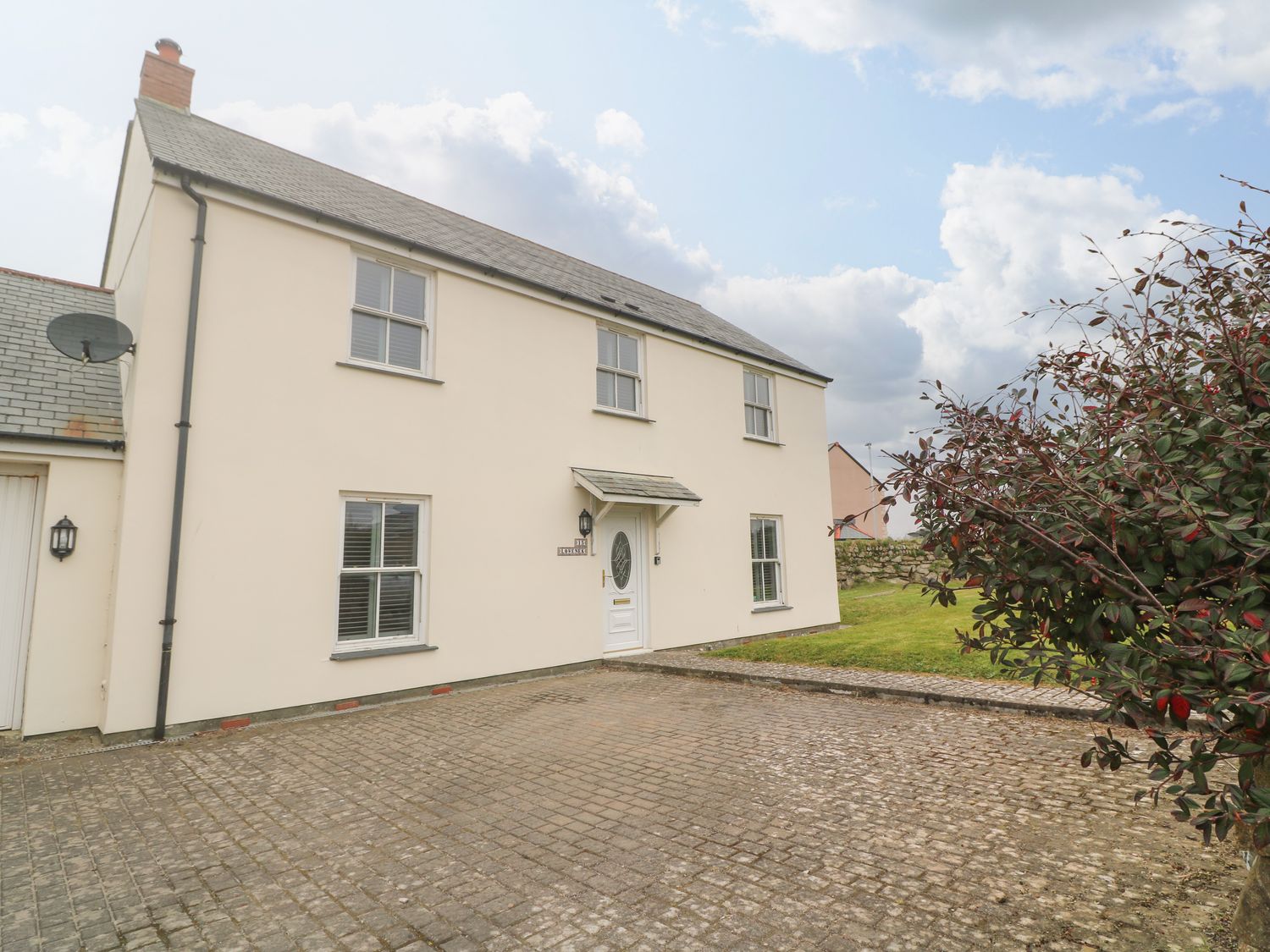 An exterior view of a two-story house with a tiled roof a paved driveway and a small garden at 15 Tower Meadows in St Buryan