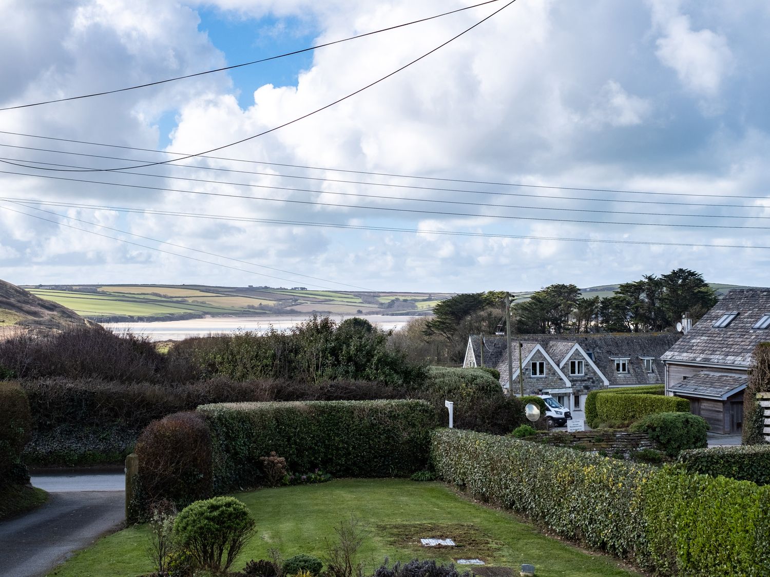 A garden and hedges with houses and fields in the background at Croft Elms in Trebetherick near Polzeath