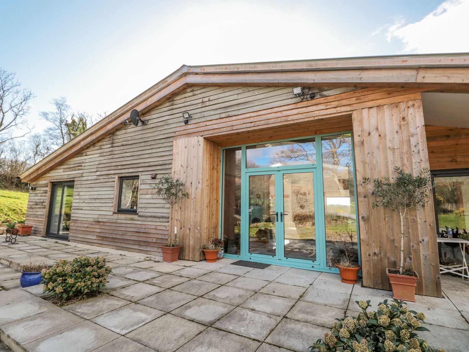 A wooden house exterior with patios and potted plants at Springfield Farm in Moreleigh near Halwell