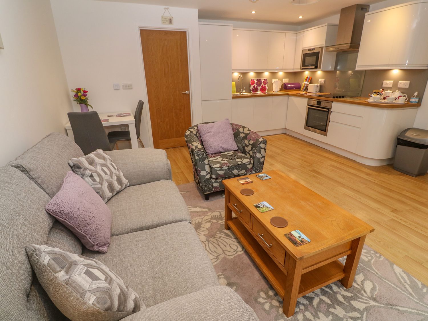 A living room with a sofa armchair coffee table and kitchen area at Pippas place in St Just
