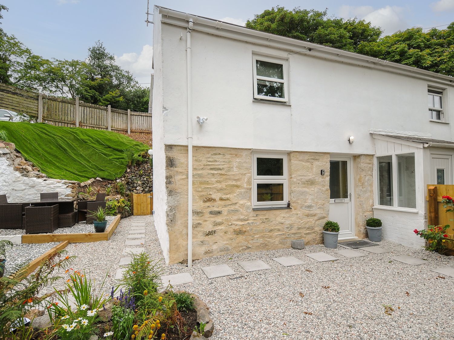A stone and white painted house with a gravel yard and outdoor seating area at The Hideaway in Chacewater