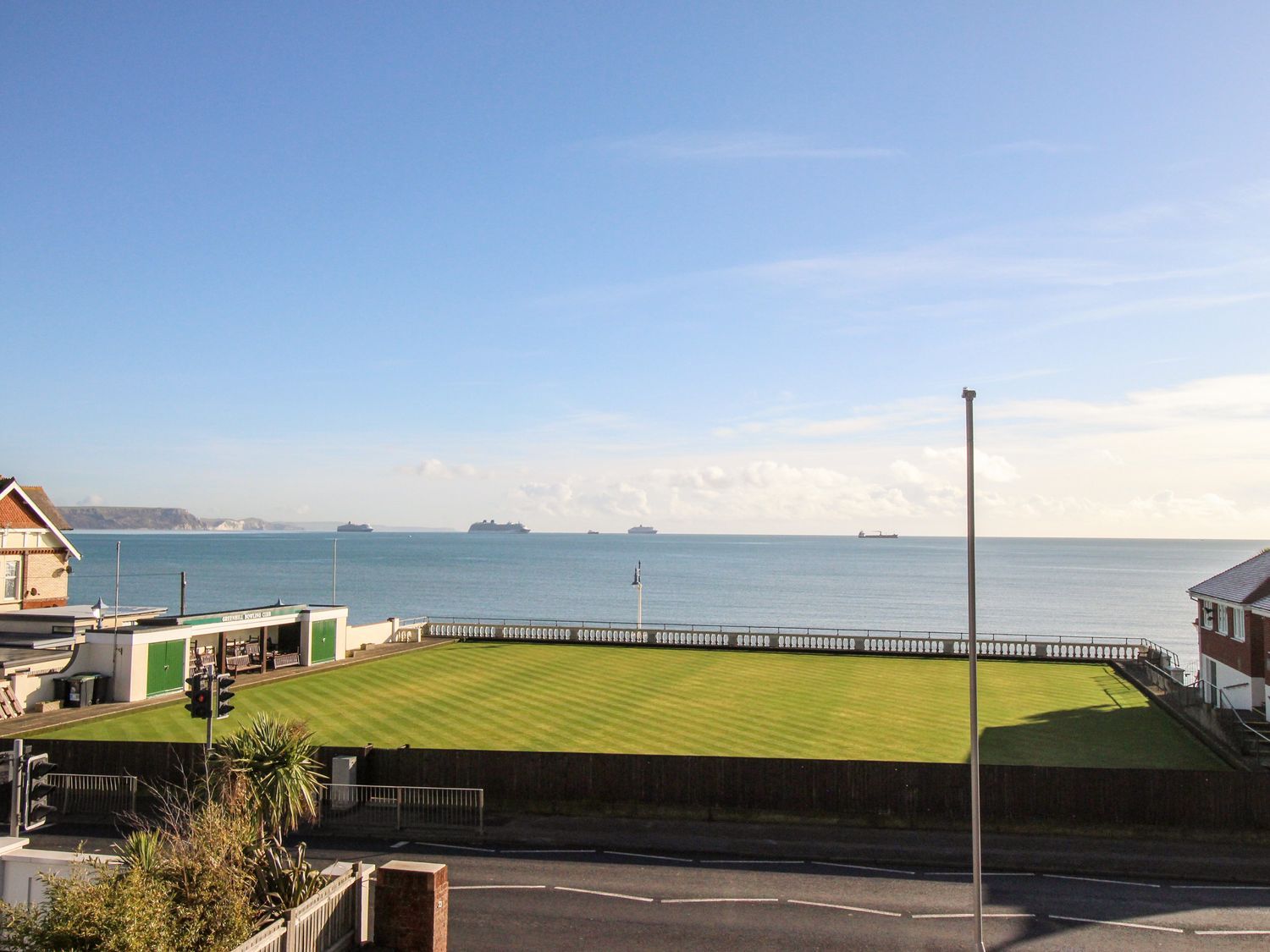 A green sports field beside the sea with ships in the water and buildings on either side at Ocean Watch 5 in Greenhill