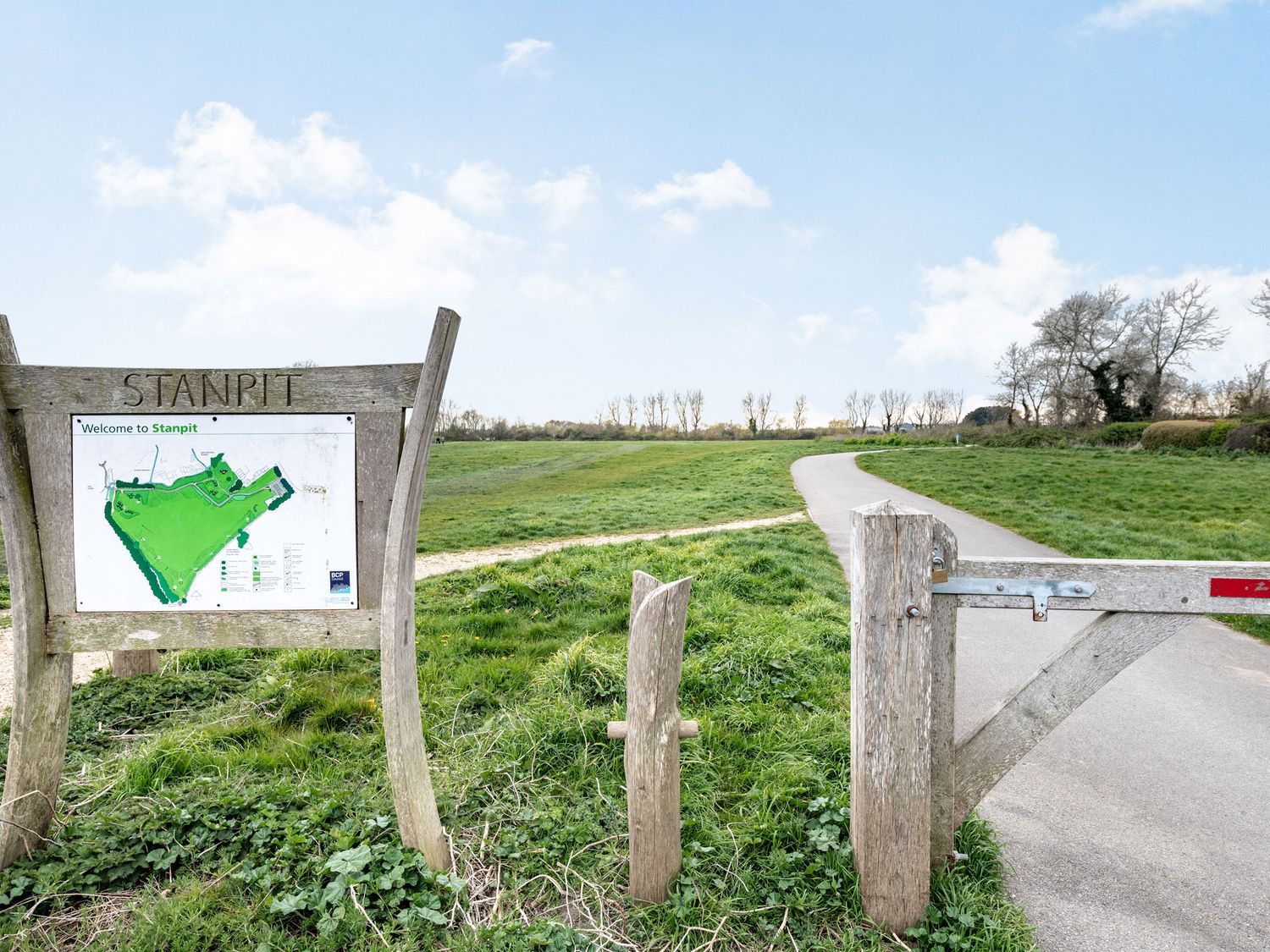 A pathway entrance with a wooden gate and a map board at Stanpit