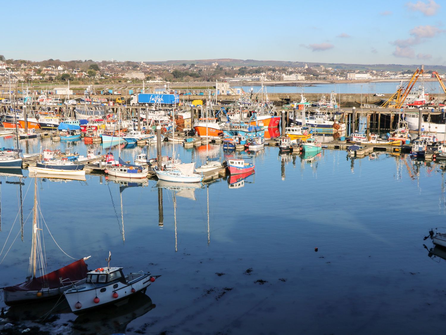 A harbor filled with various small boats and fishing vessels near a coastal town at 15 Boscaswell Downs in Pendeen