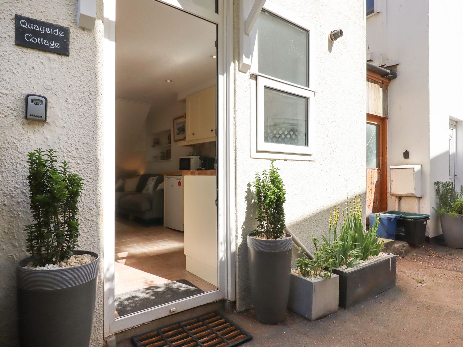 Entrance to a cottage with potted plants outside and a view into a kitchen and living area at Quayside Cottage in Teignmouth