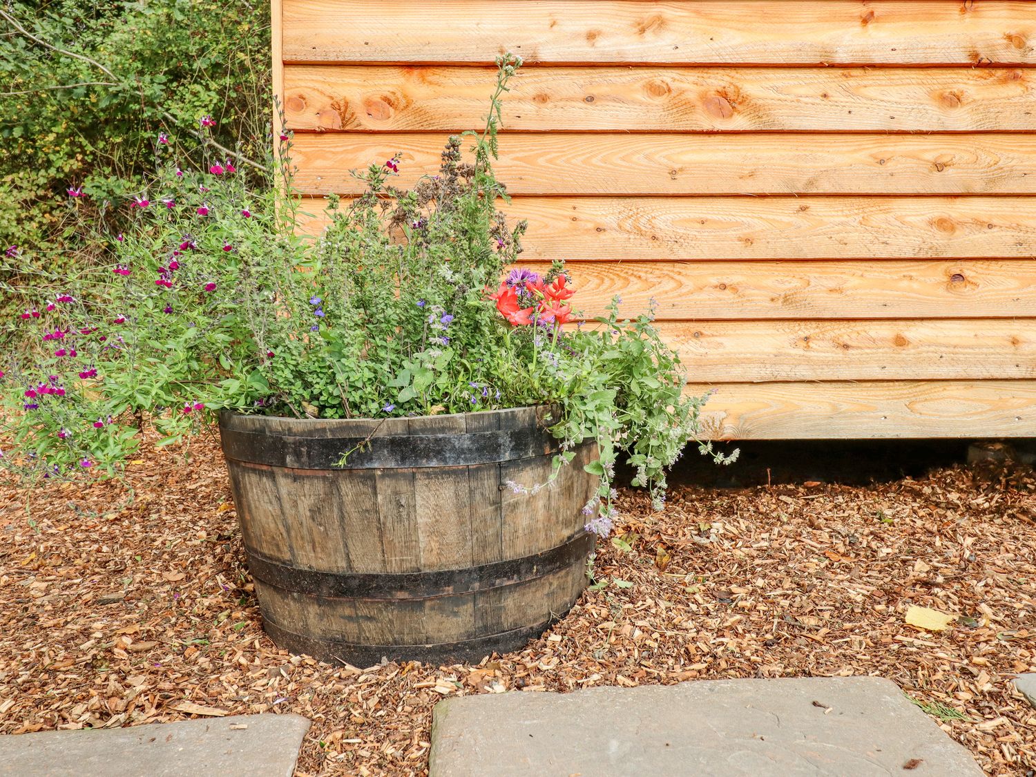 A wooden planter with various flowers and plants outside a wooden building at Hideaway Cabin in Cadbury near Thorverton