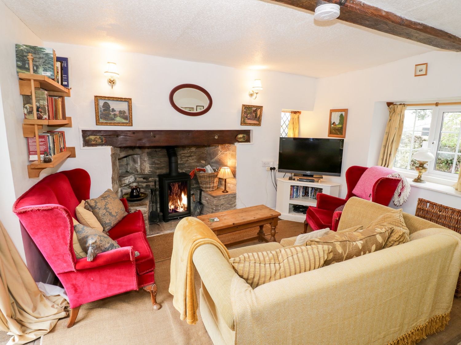 A living room with a fireplace TVshelves and sofas at Rock Cottage in Hatfield near Tenbury Wells