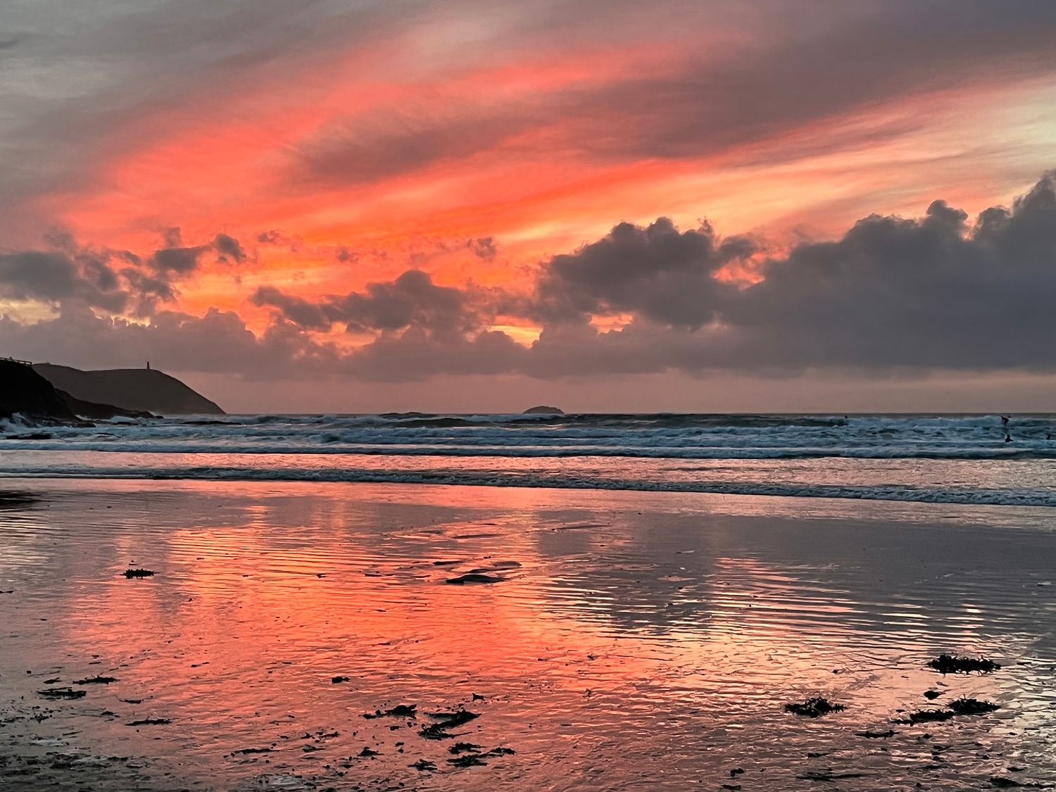 A sunset over a beach with waves and clouds at Alpha in St Minver
