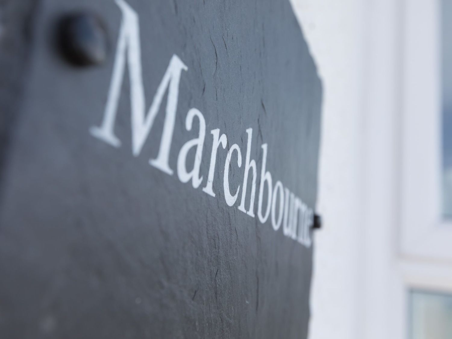 A close-up of a black plaque with the word Marchbourne written on it mounted on a white wall at Marchbourne in St Ives