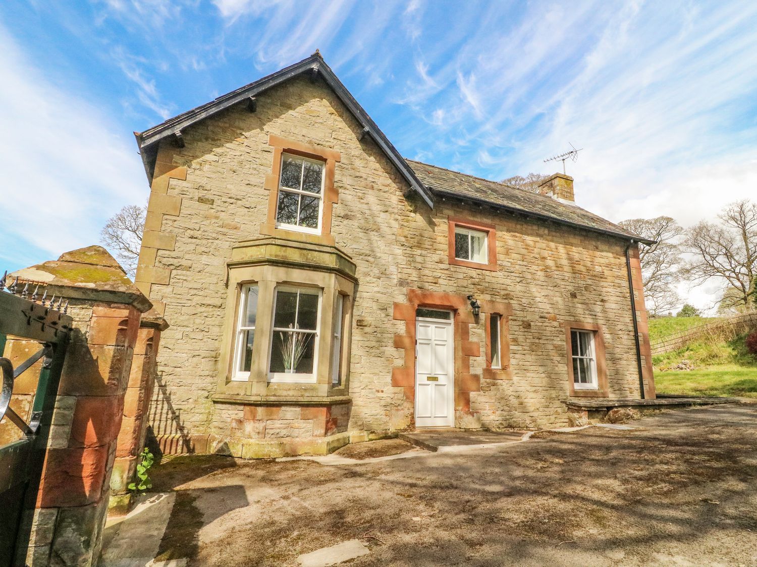 Stone house with white door and multiple windows including a bay window at South Lodge in Appleby-In-Westmorland