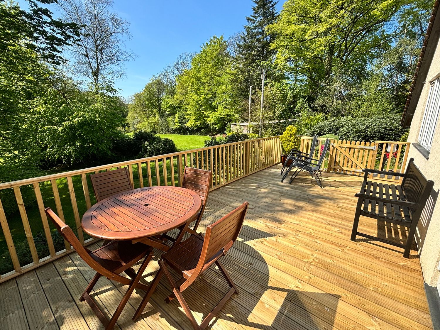 A deck with a wooden table and chairs at Little Oaklands Lostwithiel