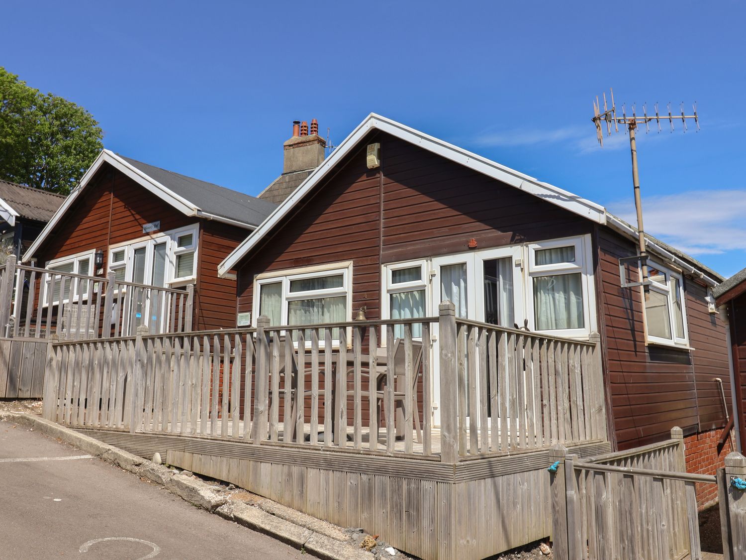 A wooden house with a fenced porch and outdoor seating under a clear blue sky at Granny's Teeth in Lyme Regis