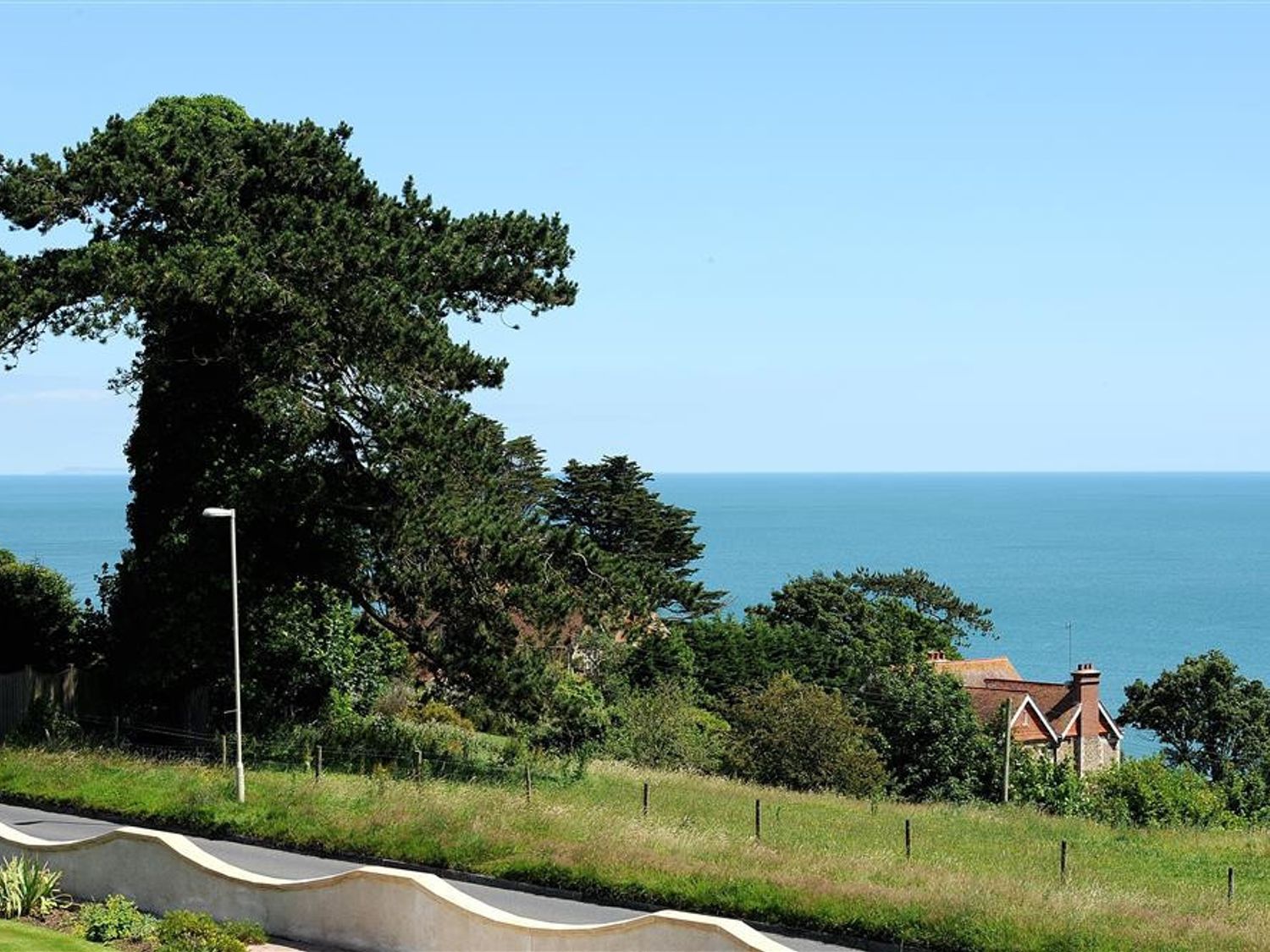 A coastal view with trees grass houses and the sea in the background at Westdale Edge in Seaton Devon