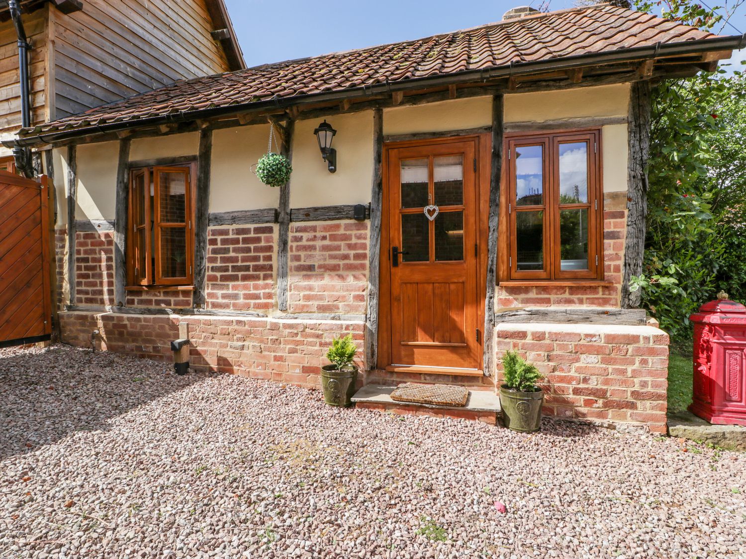 An exterior view of a brick and timber cottage with a wooden door and two windows at The Forge in Tarrington near Bartestree