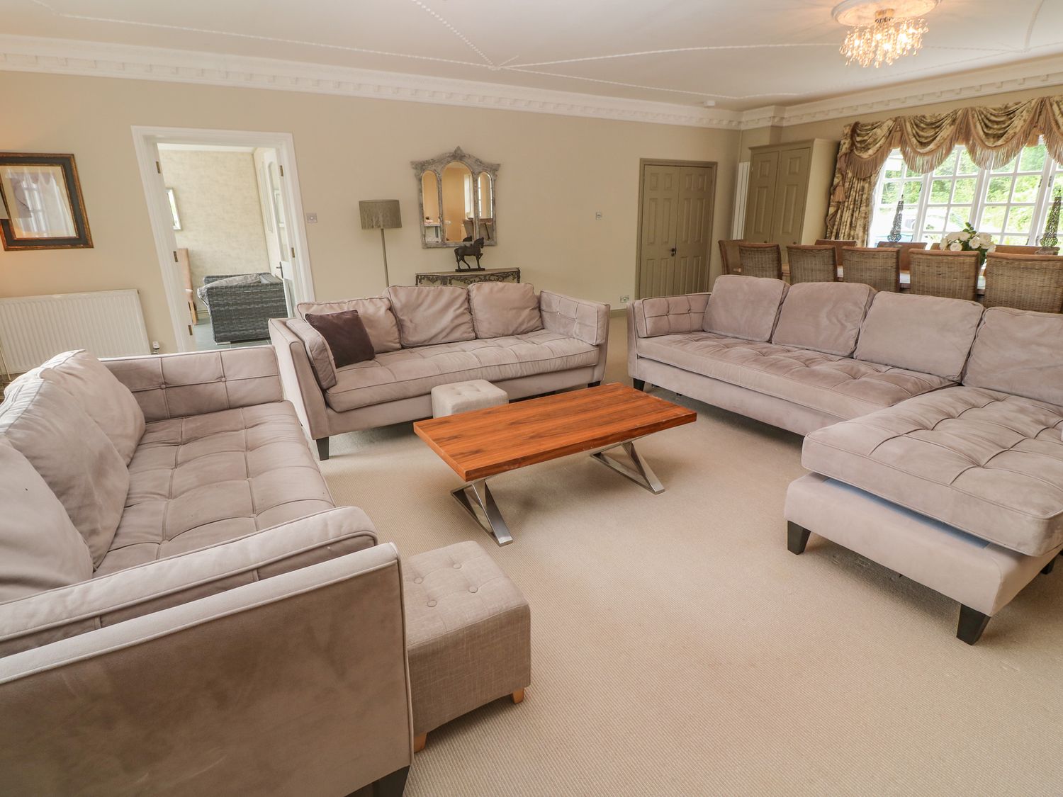 A living room with three sofas a wooden coffee table and a dining table with chairs at Bodmin Country House in Lanivet