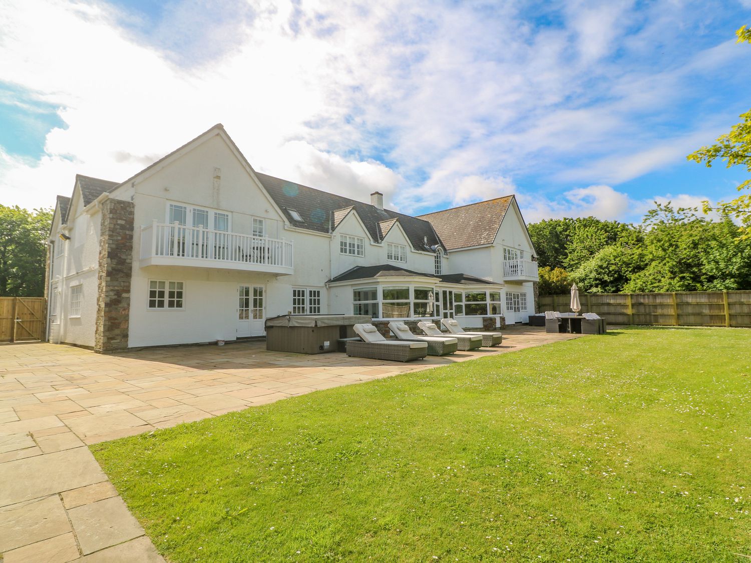 An outdoor patio area with loungers tables and a large garden at Bodmin Country House in Lanivet