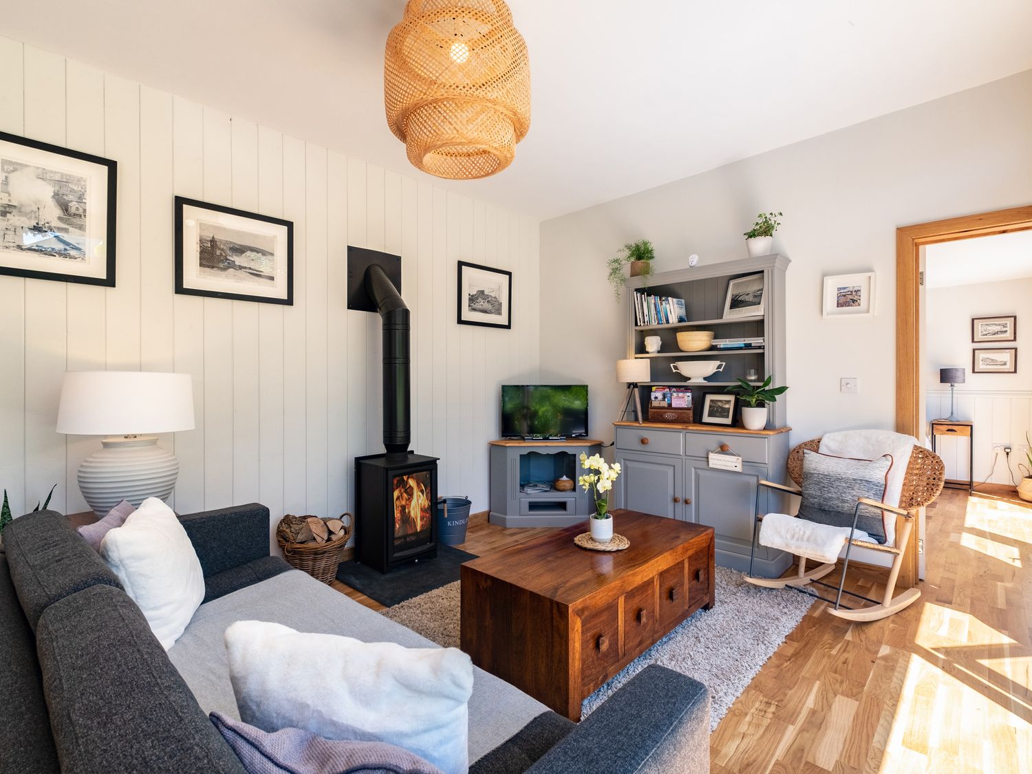 A living room with a sofa a rocking chair a wood stove a wooden coffee table and a grey cabinet at Chi Lowarth in Porthleven