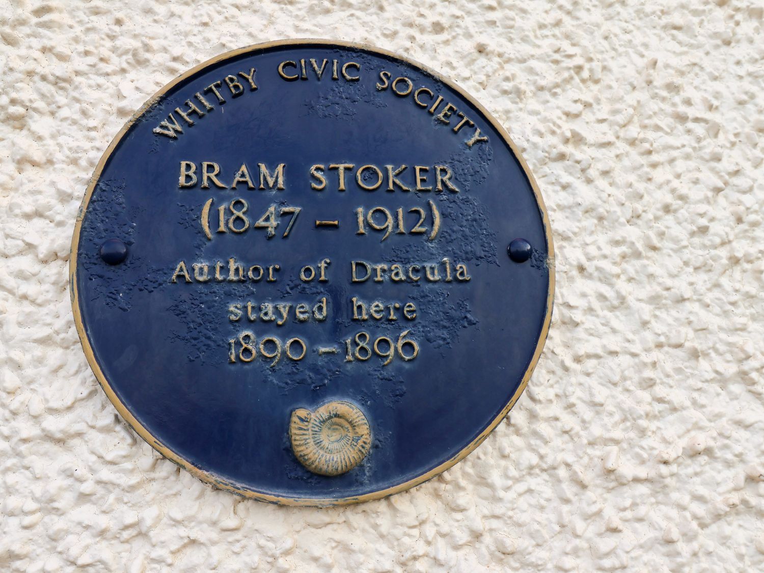 A blue plaque on a textured white wall commemorating Bram Stoker at Brams Lair in Whitby