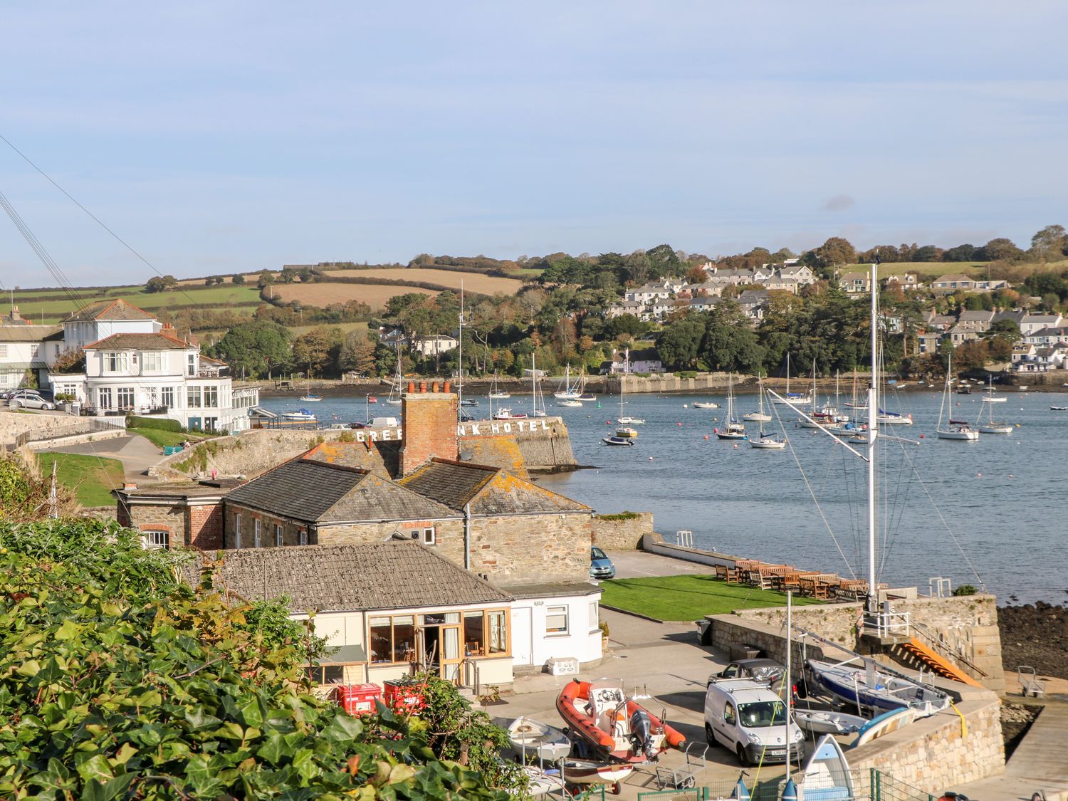 A harbor with boats docked and houses on hills in the background at Flat 6 in Falmouth