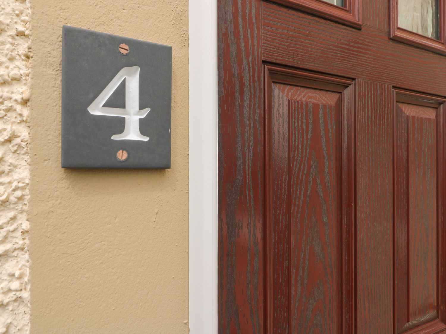 A dark wood door next to a wall with a number 4 plaque at Flat 4 in Solva