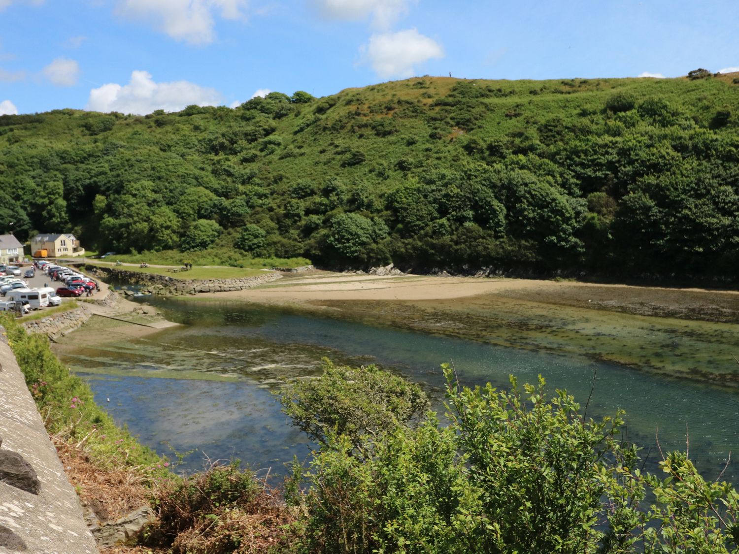 A river or inlet with clear water bordered by green hills cars parked near houses on the left side at Flat 4 Solva