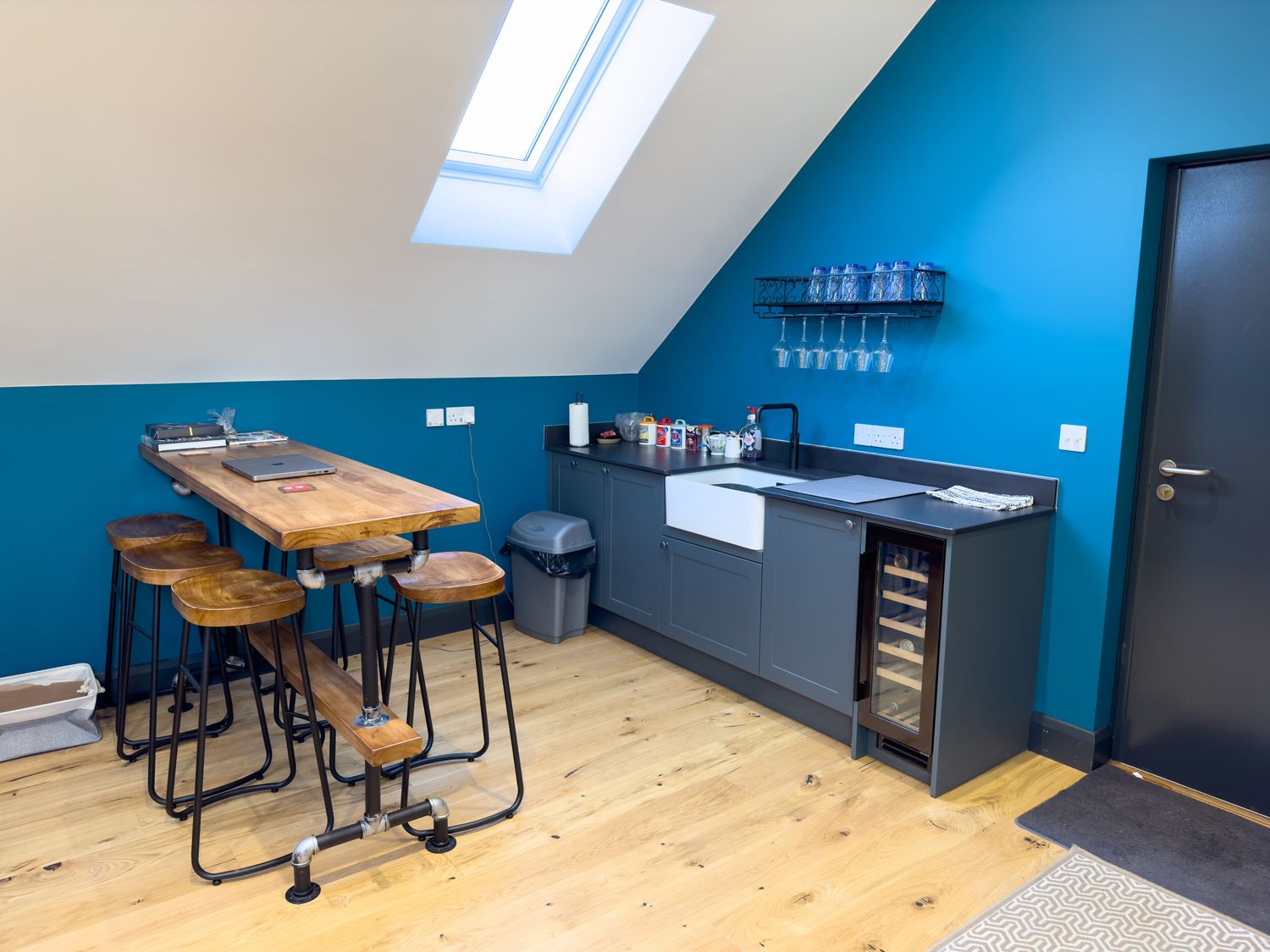 A kitchen area with a wooden table and stools a sink wine cooler and glass rack at Pen- y- Bryn @ Canllefaes in Penparc near Cardigan