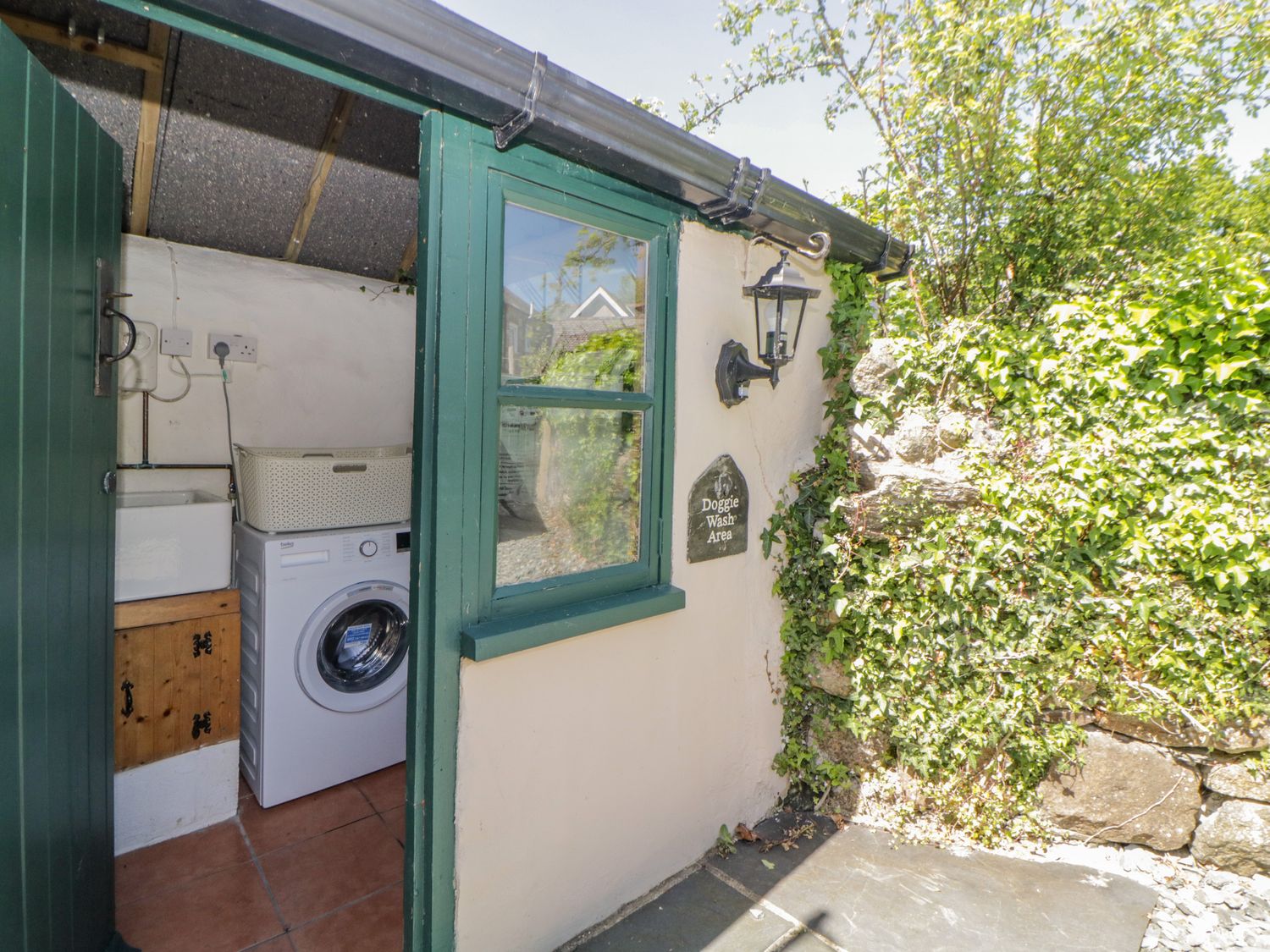 An outdoor utility area with a washing machine and a sign reading doggie wash area at Burham Cottage Walkhampton near Yelverton
